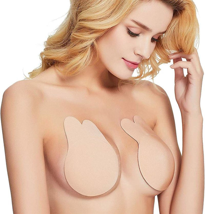 A woman with long blonde hair wears Shapelux Lifting Pads for Invisible Breast Lift, a beige strapless bra alternative with strong adhesive tape, offering a discreet lift. She looks down slightly, her expression neutral.