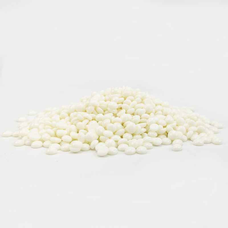 A pile of small, round, white UNIQ Nose Wax Kit pellets for nose hair removal by UNIQ is scattered on a plain white surface with a white background.